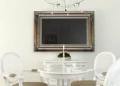 Thumbnail of a beautiful mirror TV with an ornate frame, mounted above a dining table in a chic room.